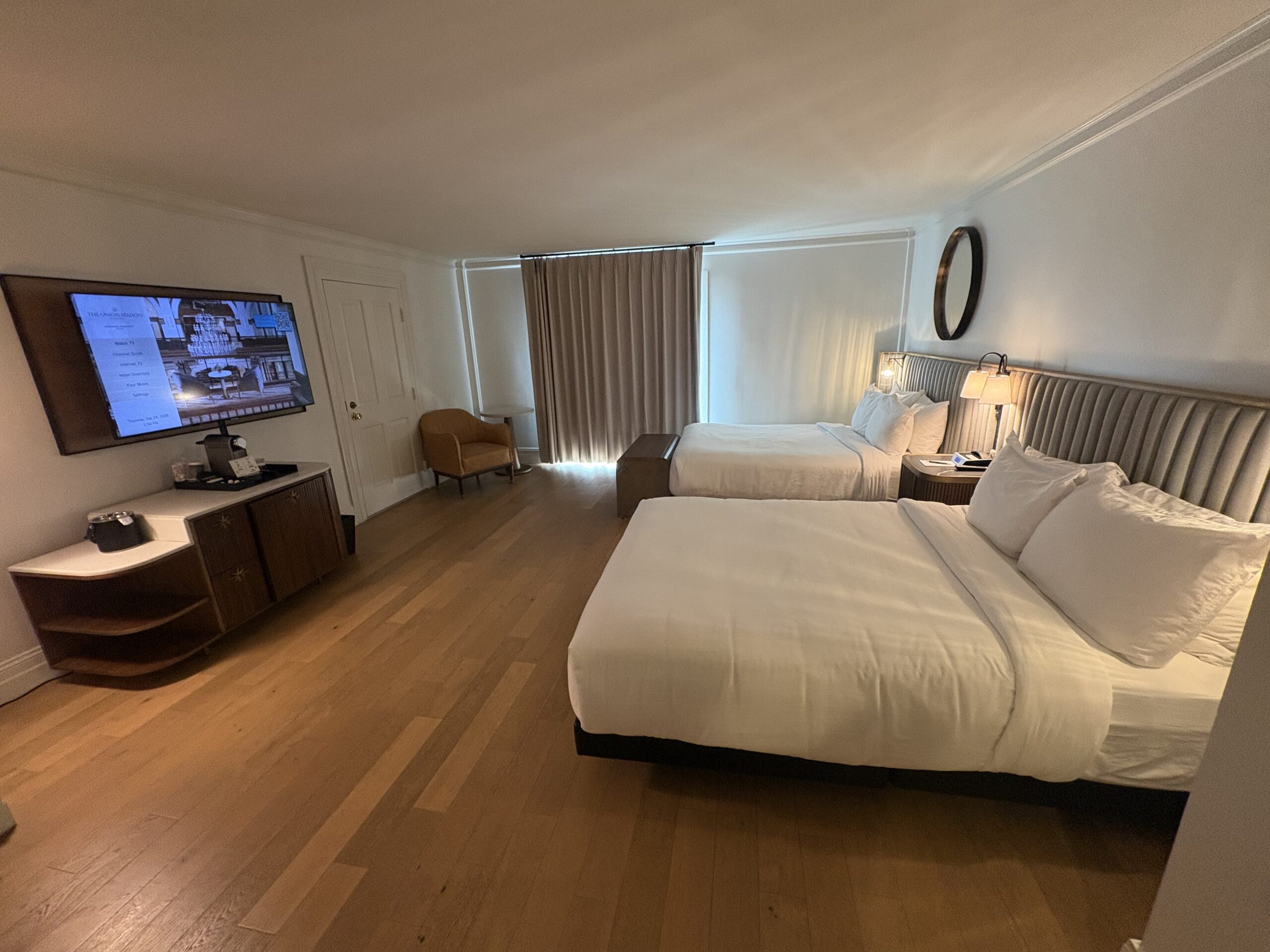 Hotel room with two queen beds, long channel-tufted headboard, hardwood floors, TV, and Nespresso station