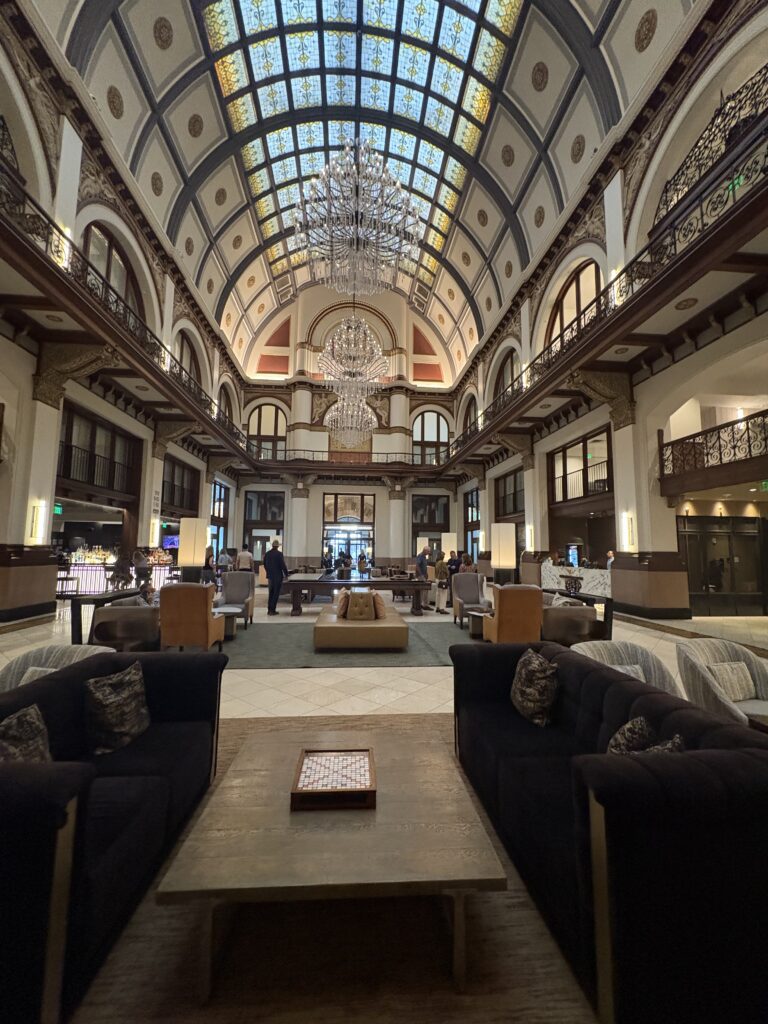 Grand lobby of Union Station Nashville Yards with stained-glass barrel-vaulted ceiling, crystal chandeliers, and iron balconies