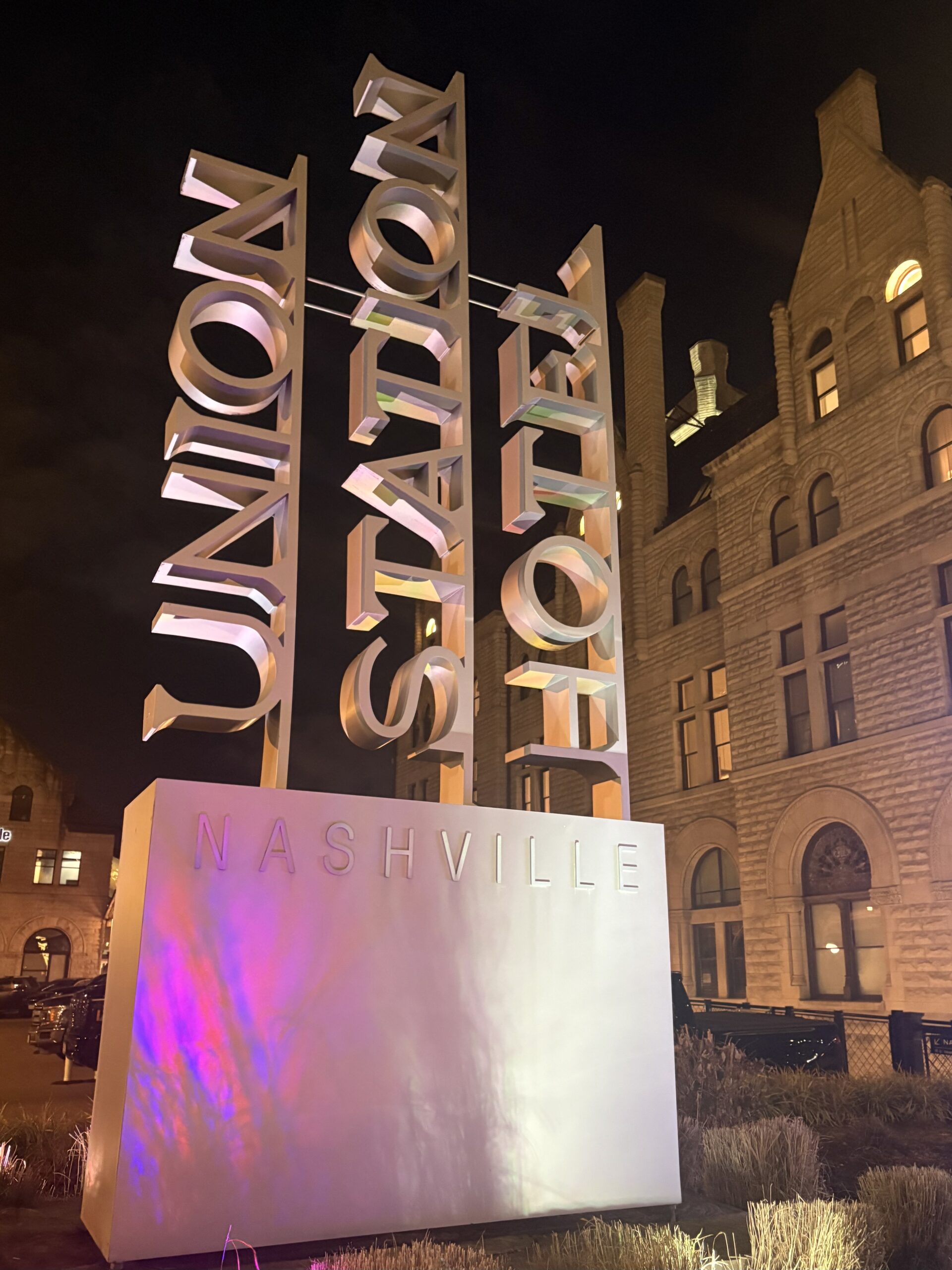 Illuminated Union Station Hotel Nashville letter sculpture in front of the historic stone hotel at night