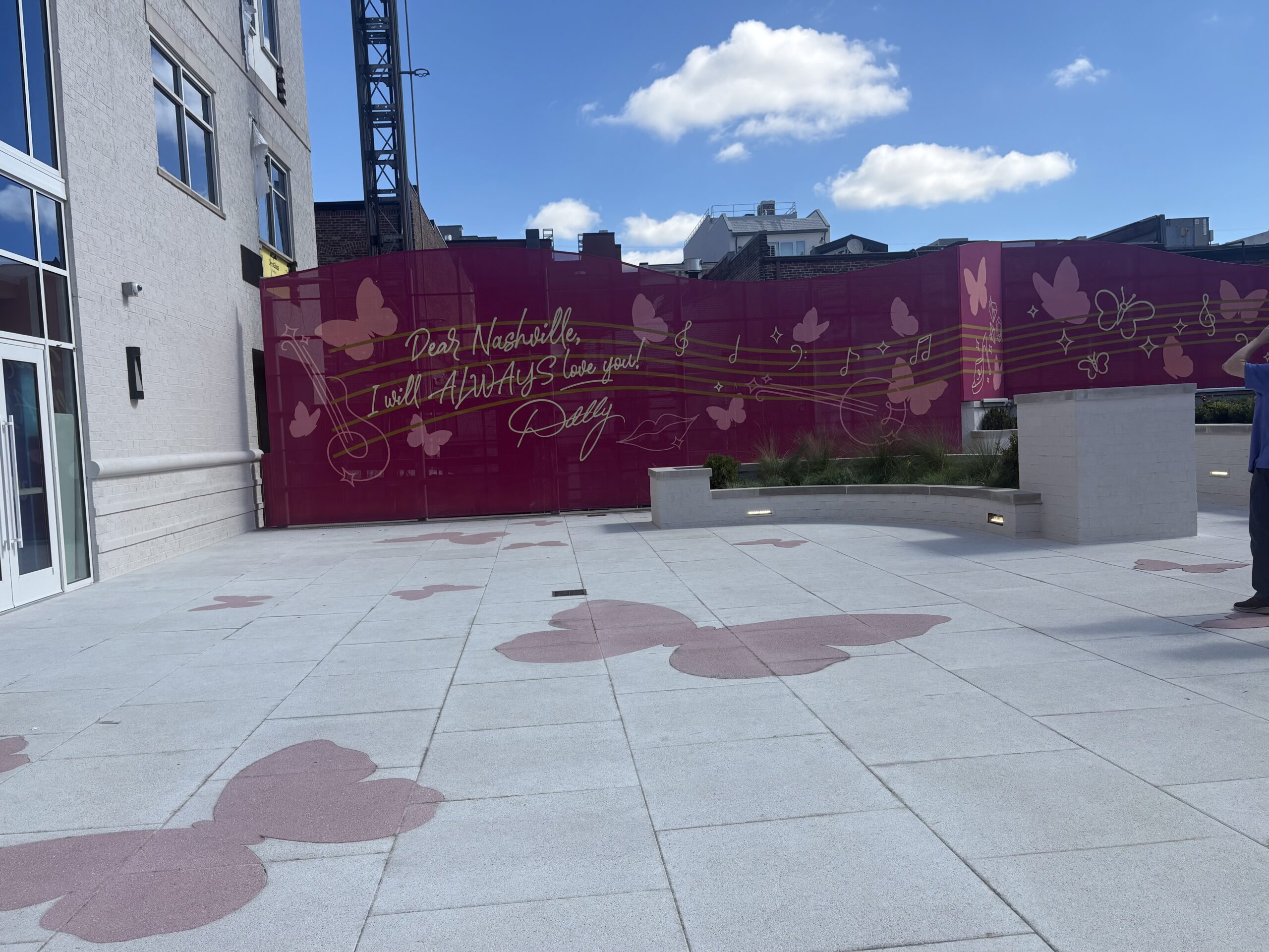 Pink wall with Dolly Parton's handwritten-style message to Nashville, surrounded by butterflies and music notes