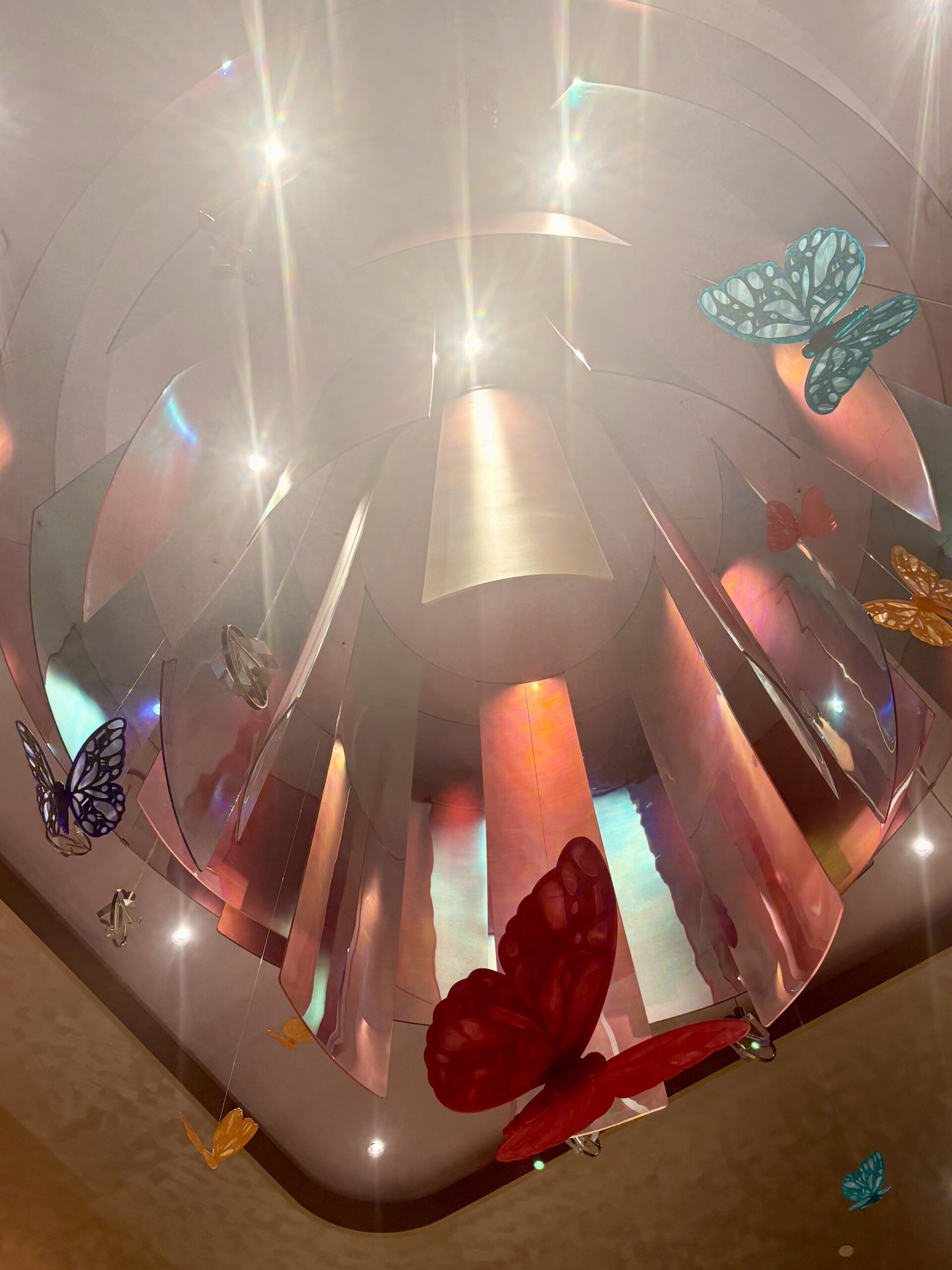 Iridescent chandelier surrounded by colorful suspended butterflies in the SongTeller Hotel lobby
