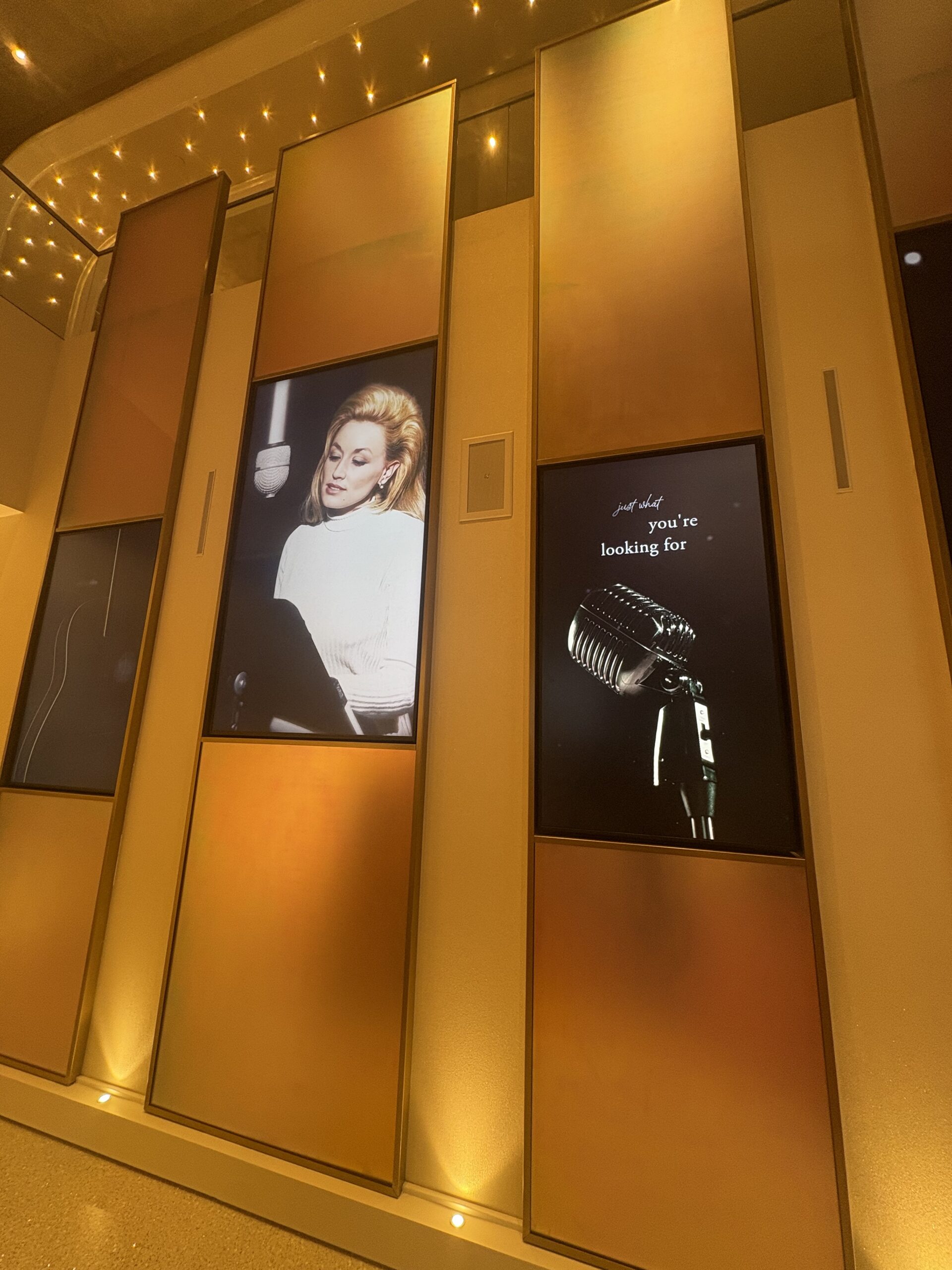 Gold lobby panels with digital screens showing a vintage Dolly Parton photo and a classic microphone