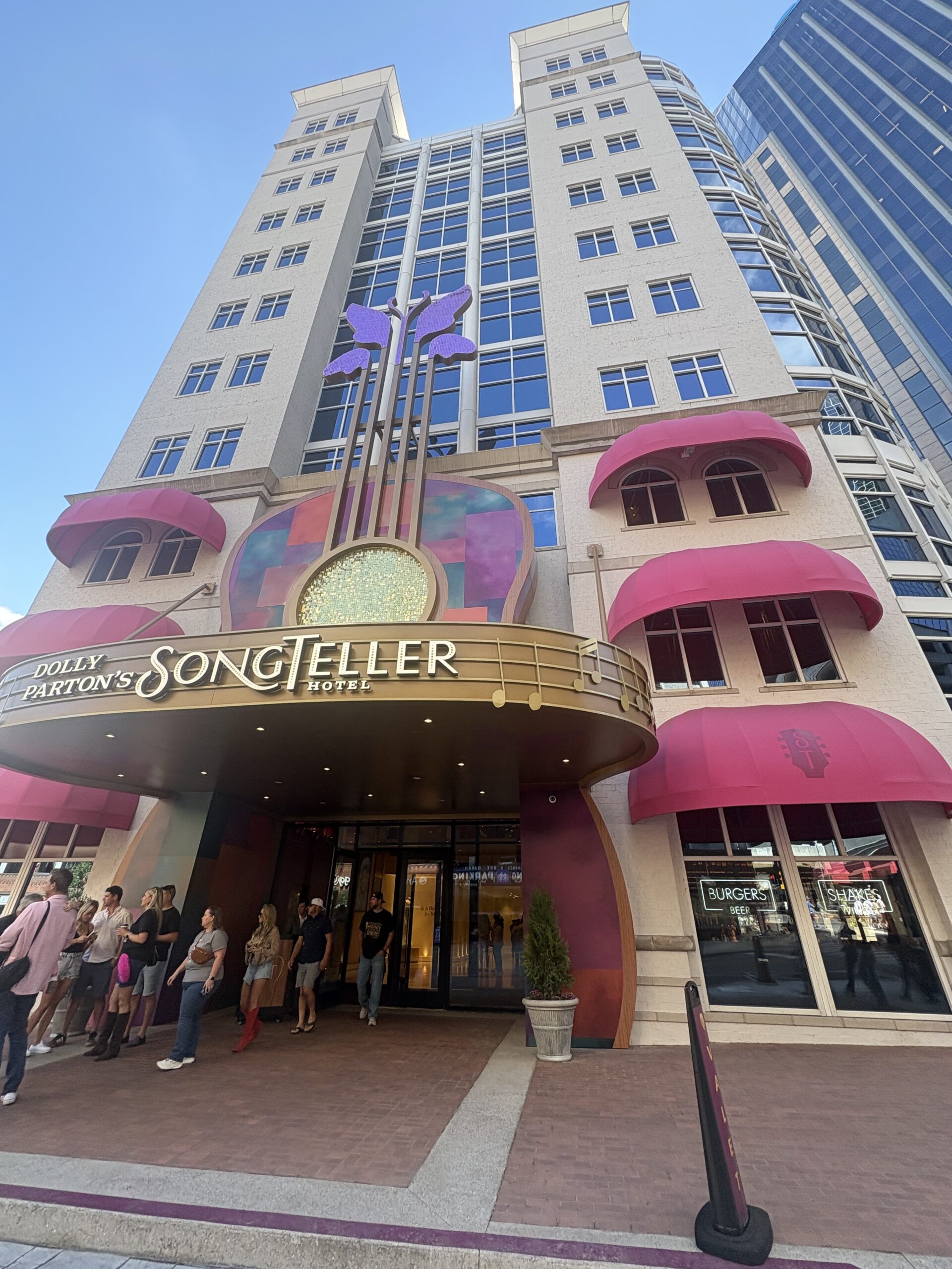 Dolly Parton's SongTeller Hotel entrance in downtown Nashville with a giant guitar facade and pink awnings