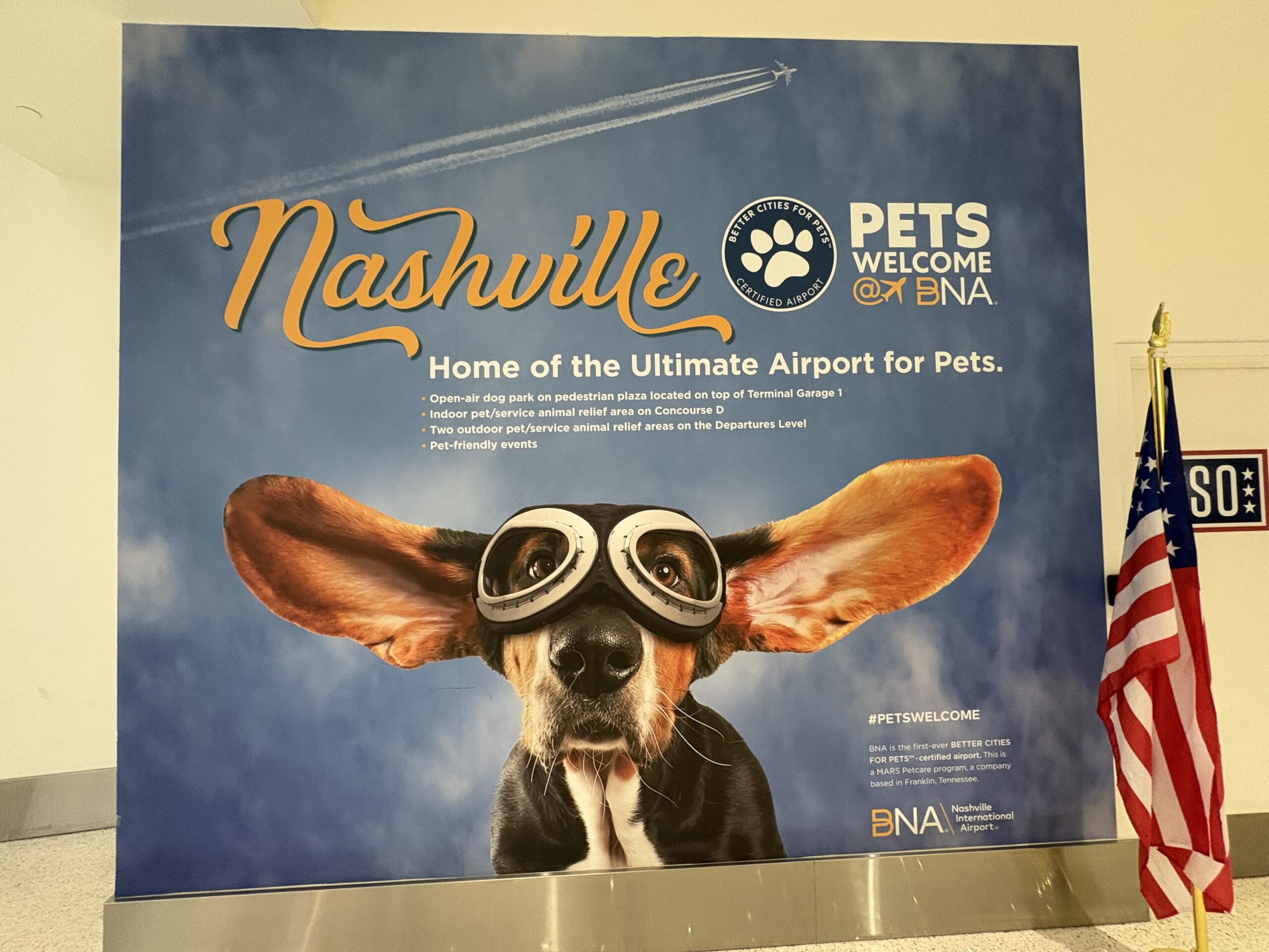 BNA Pets Welcome sign with a basset hound in aviator goggles, listing the airport's dog park and pet relief areas